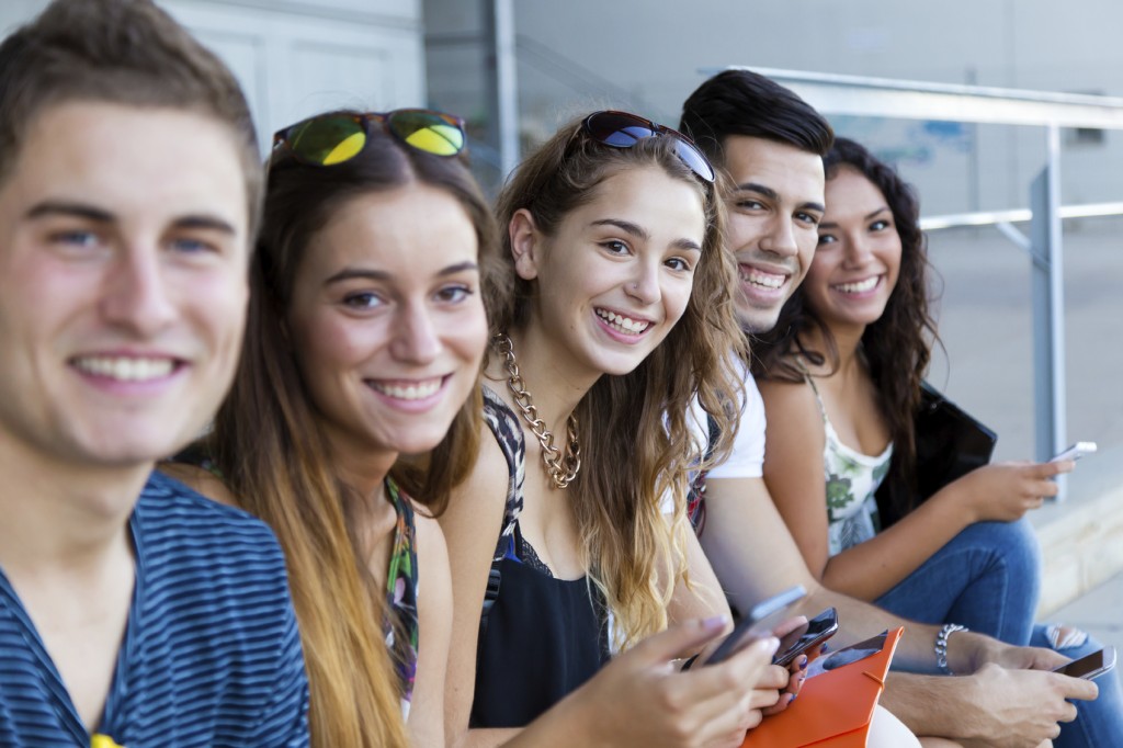 A group of students having fun with smartphones after class.