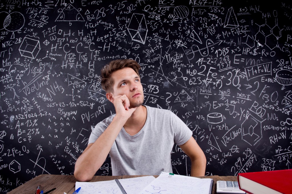 Hipster student doing his homework against a big blackboard
