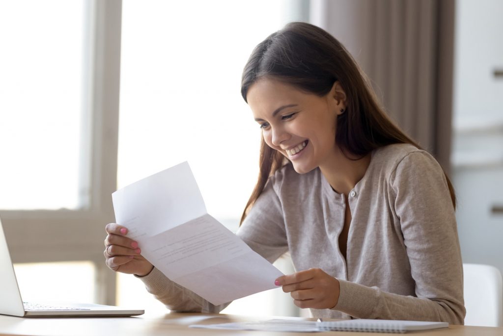 women, reading letter with results, she's happy