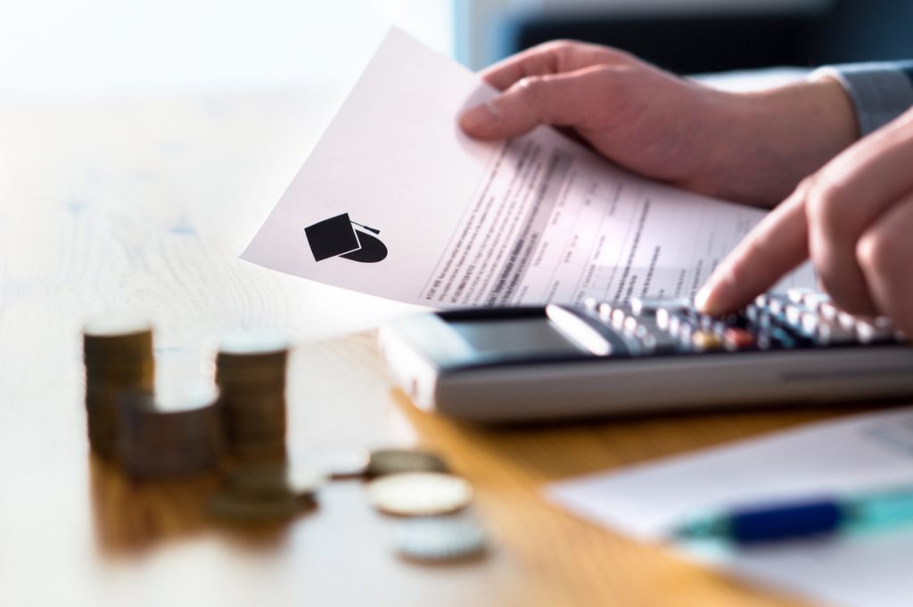 Student working out budget with student finance letter and calculator