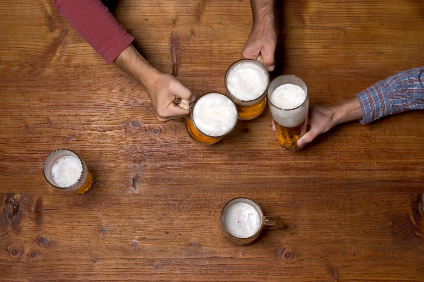 three people drinking beer at the wooden table at pub