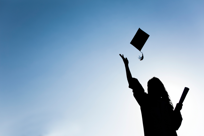 Graduate students tossing up hats over blue sky